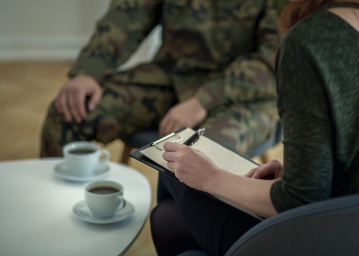 Close-up of psychologist writing down notes while talking to her Close-up of psychologist writing down notes while talking to her patient from army